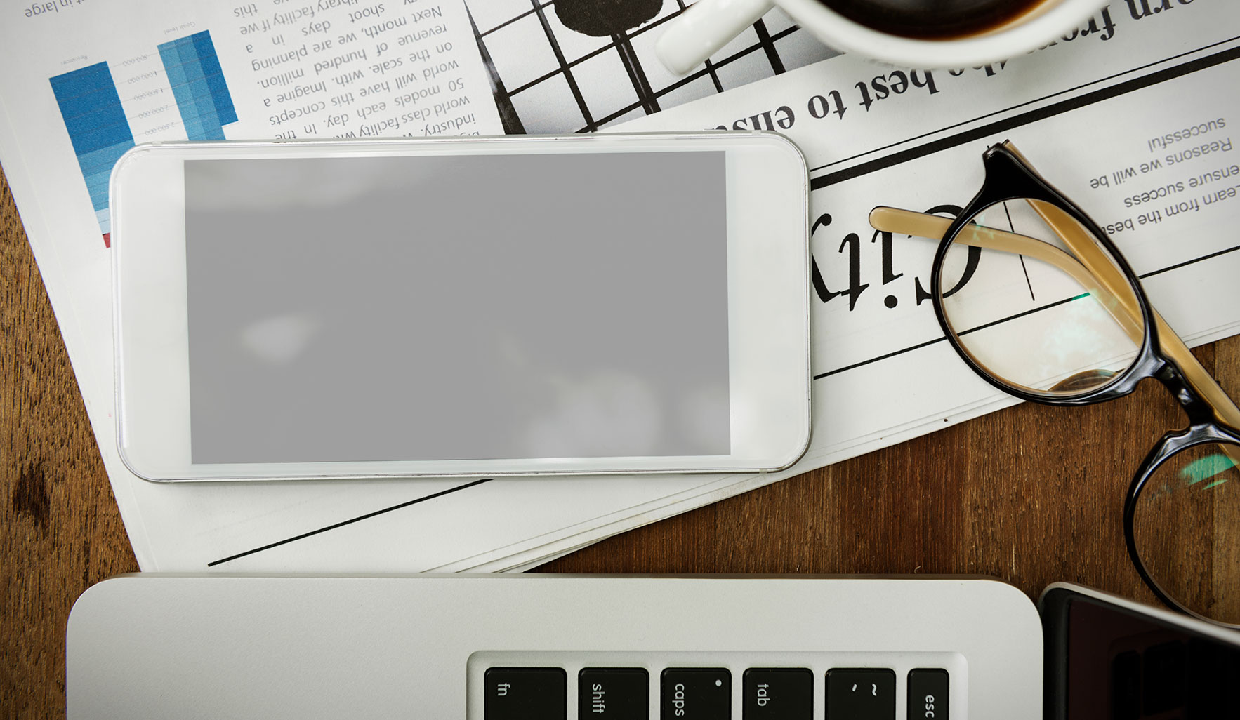 newspaper and laptop with reading glasses